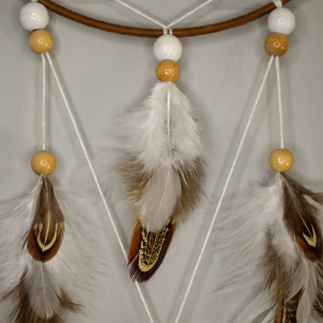 Zoom sur les plumes blanches et naturelles de l’attrape-rêve Alizé Nomade, perles bois clair et blanches, création artisanale unique.