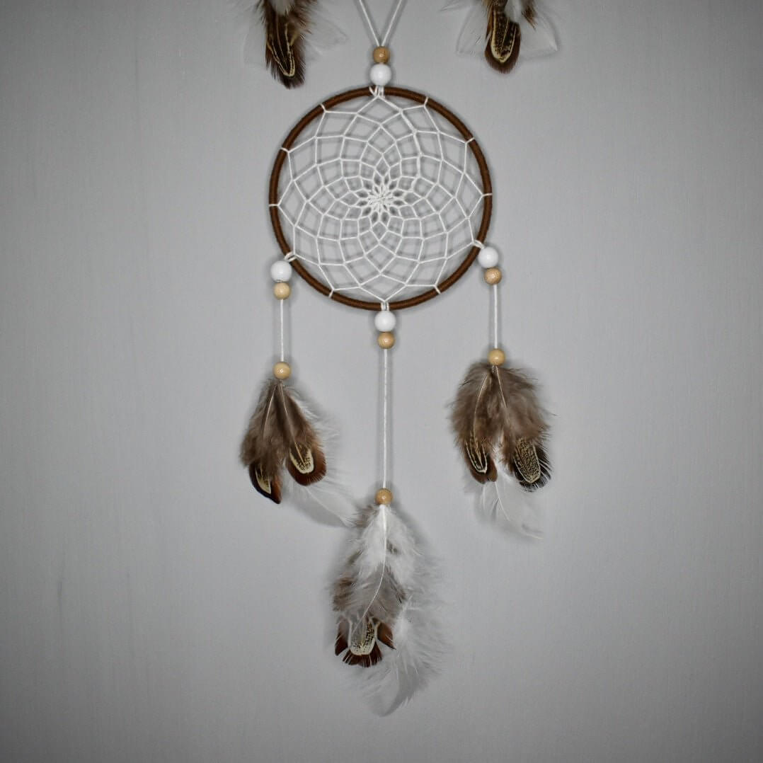 Détail du second cercle de l’attrape-rêve Alizé Nomade, tissage brun et blanc, perles bois clair et blanches, plumes blanches et naturelles.