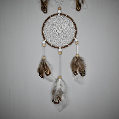 Détail du second cercle de l’attrape-rêve Alizé Nomade, tissage brun et blanc, perles bois clair et blanches, plumes blanches et naturelles.