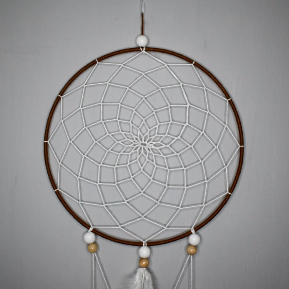 Détail du premier cercle de l’attrape-rêve Alizé Nomade, tissage brun et blanc, perles bois clair et blanches, plumes blanches et naturelles.