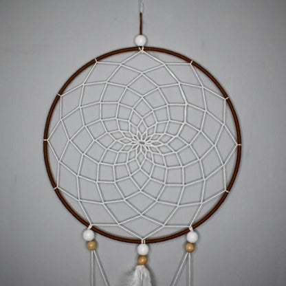 Détail du premier cercle de l’attrape-rêve Alizé Nomade, tissage brun et blanc, perles bois clair et blanches, plumes blanches et naturelles.