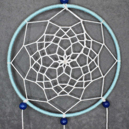 Détail du tissage étoile à 8 branches style fleur de lotus, fil bleu ciel et blanc, perles bois bleu, plumes assorties.